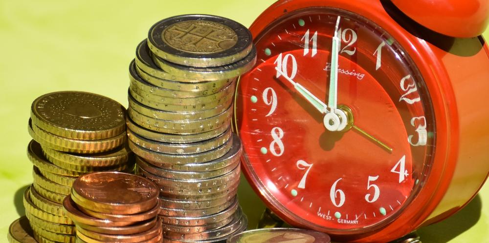 Pila de monedas junto a un reloj despertador